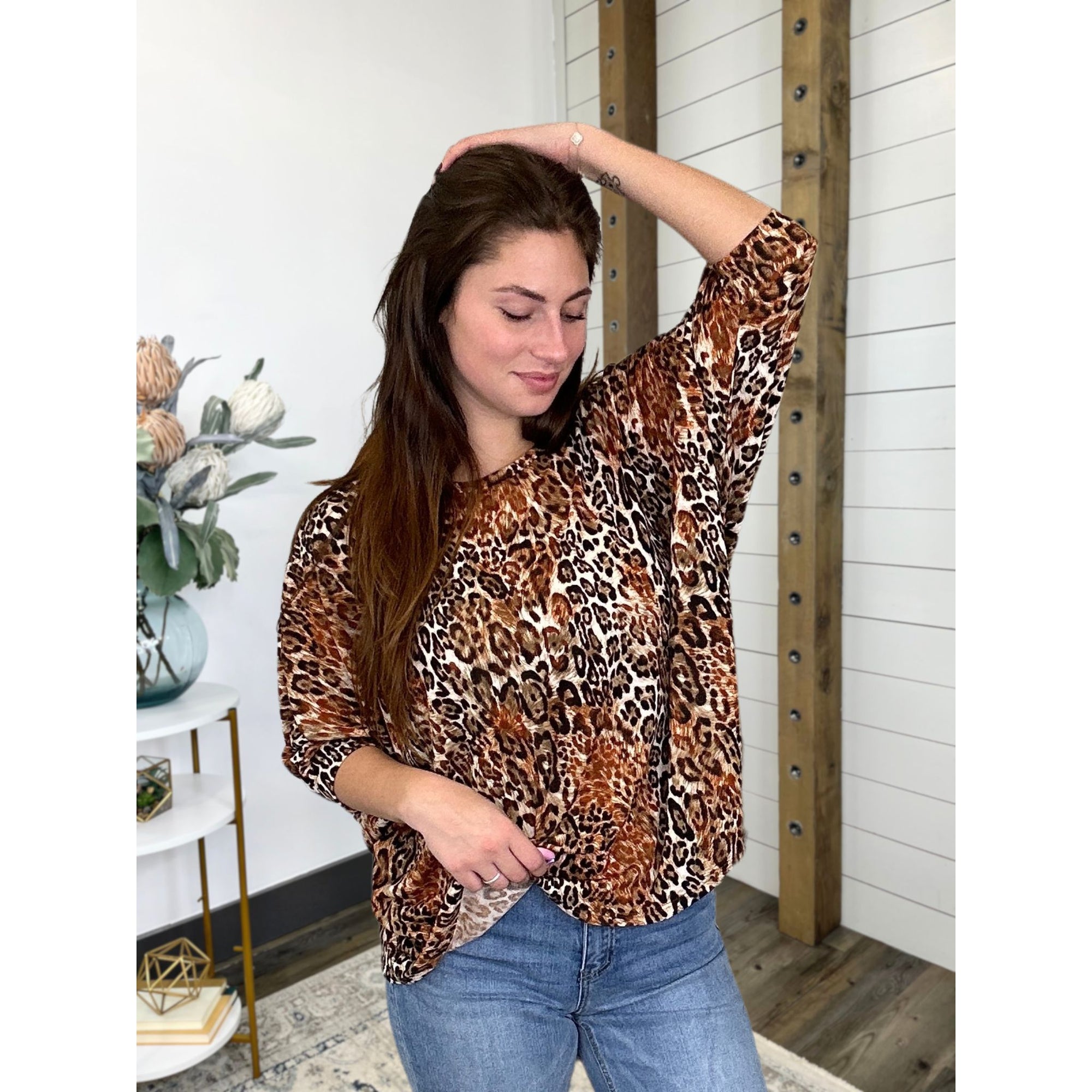 A woman wearing a leopard print, 3/4 dolman sleeve, round neck top.